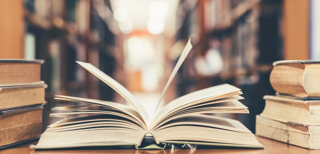 Open book in front of book shelves.