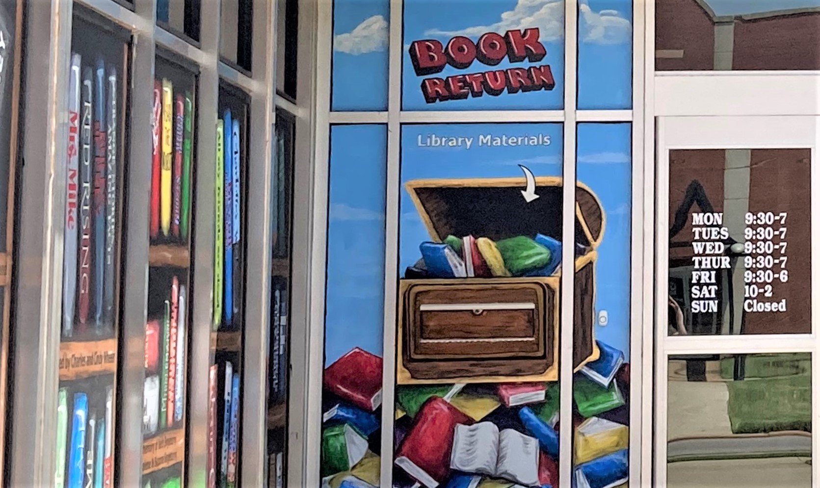 Image: Photo of the book return by the front door of the library with hours of operation visible on the doors.