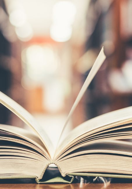 Open book in front of book shelves.